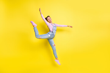 Photo of carefree dancer lady jump make piruet wear jeans overall footwear isolated yellow background