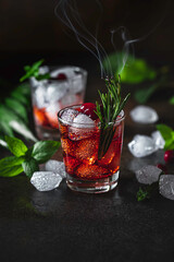Berry alcoholic cocktail liqueur, vodka, ice and rosemary. Refreshing cool drink, berry liqueur or red alcoholic cocktail. - obrazy, fototapety, plakaty