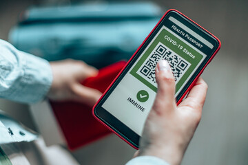 Young girl hand holding a passport, ticket pass and smartphone with digital health passport app for travel during covid-19 pandemic.
