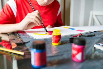 Child painting with watercolor with primary colors. The color red predominates