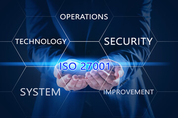 Businessman demonstrating text ISO 27001 on dark background, closeup