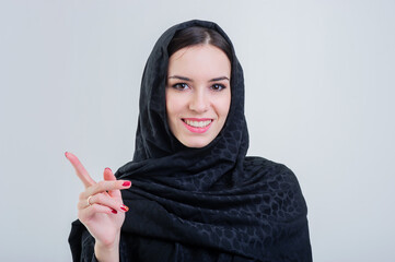 Beautiful arab woman with pointing finger isolated on grey background