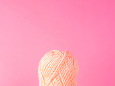 Spool of yarn on pink background