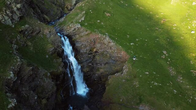 Circular travelling view of a waterfall formed by thaw in a mountain valley