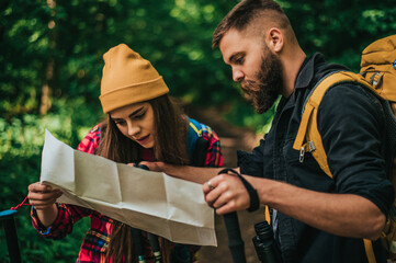 Couple of hikers using trekking poles and map while spending the day in nature