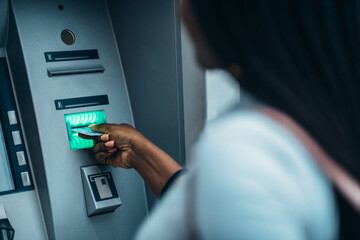 African american woman using credit card and withdrawing cash at the ATM
