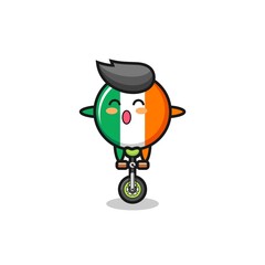 The cute ireland flag badge character is riding a circus bike