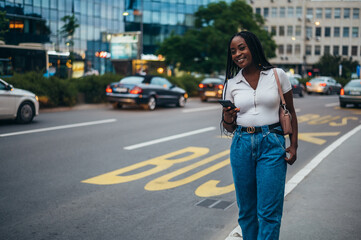 Cheerful african american woman using smartphone while on the bus stop