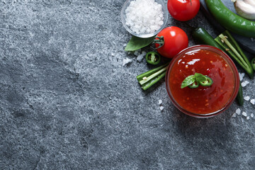 Spicy chili sauce and ingredients on grey table, flat lay. Space for text