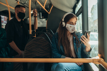 Obraz na płótnie Canvas Young woman wearing protective mask and using smartphone while riding a bus