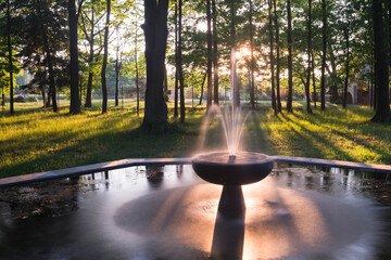 Park Dworski w Iłowej. Parkowa fontanna w ciepłym świetle zachodzącego słońca.