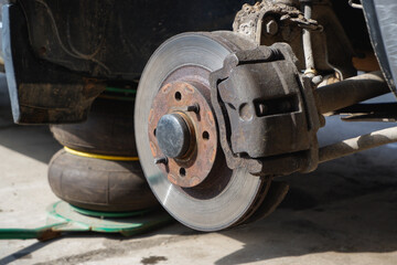 Car repair. Car with removed wheels on pneumatic jacks. View of the brake discs hub.