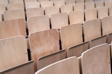 Empty collapsible wooden chairs in auditorium background. Higher education at university or college.