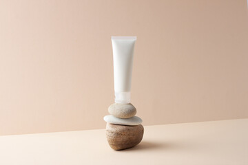 White tube of cosmetic cream on a stone podium on beige background. Close up.