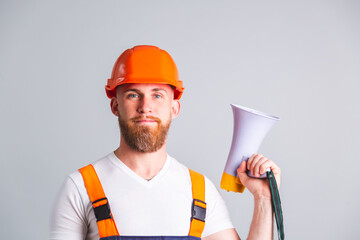Handsome man engineer in building protective helmet on gray background shouting screaming in...