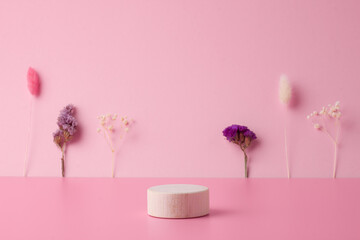 Cosmetic background with wooden podium and flowers on pink. Empty showcase for cosmetic product presentation.