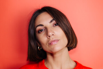 Fototapeta premium Close portrait of woman on red background looks to camera