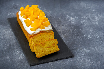 mango pound cake with whipped cream on grey background