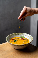 Seasonal winter pumpkin soup with fragrant herbs and olive oil on modern gray stone background