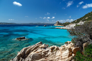 Obraz premium Scenic rocky coast in Sardinia, rock formation in the foreground and yachts in the horizon, sea with azure crystal clear water. Sardinia, Italy.