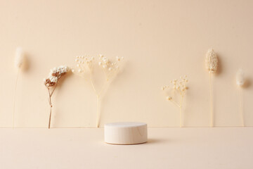Cosmetic background with wooden podium and flowers on beige. Empty showcase for cosmetic product presentation.