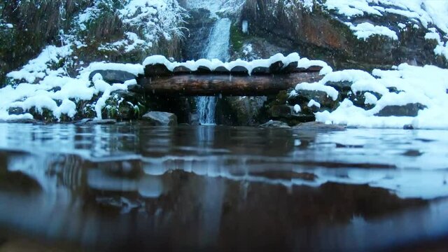 View of the Jana Waterfall during the snowfall at Manali, Himachal Pradesh, India. Camera slowly moves from underwater to above, Travel Concept. Snowfall in Manali during the winter.