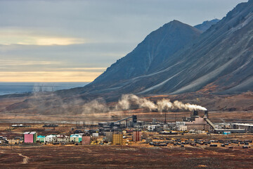 Industrial Arctic landscape. View of the industrial area in the tundra. Fuming chimneys of a power plant. Industry and ecology of the polar region. Ozyorny, Egvekinot, Chukotka, Far North of Russia.