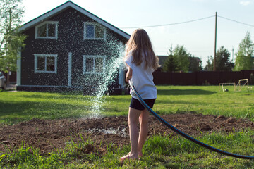 girl is hosing down a vegetable garden