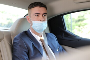 Businessman wearing protective mask incorrectly in backseat