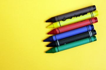 Fototapeta premium Colored pencils on a yellow background. Lots of different colored wax pencils. Colored pencil. Drawing lessons, hobbies, education, creativity. Close-up. Copy space. Background. Flat lay.