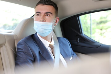 Businessman wearing protective mask incorrectly in backseat 