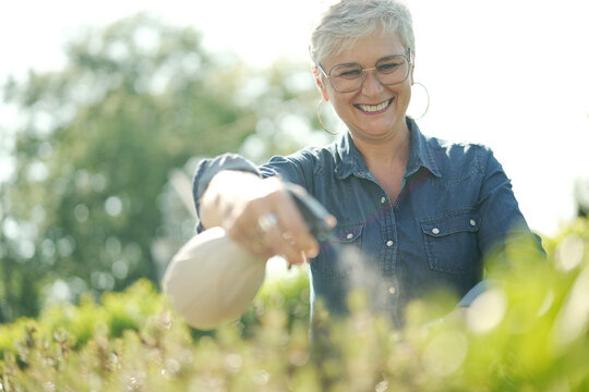 Portrait Of A 55 Year Old Senior Woman Watering Plants In Her Garden