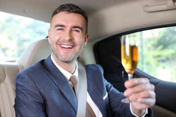 Rich and sexy man drinking champagne in limousine