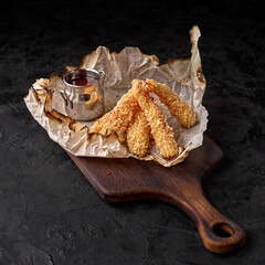 crispy fried chicken nuggets with tomato sauce. Tasty snack for beer on a dark background