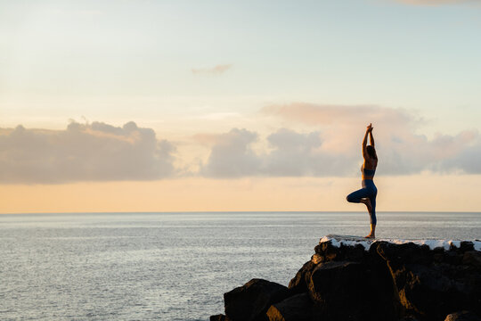 Faceless woman performing Tree with Arms Up pose against sea