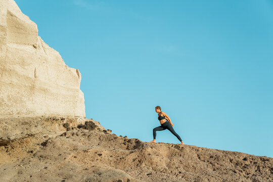 Woman standing in humble warrior pose near big rocks