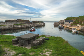 a wooden boat in a body of water in Ballintoy Harbour by Ballycastle in Antrim, Northern Ireland, location for major tv show