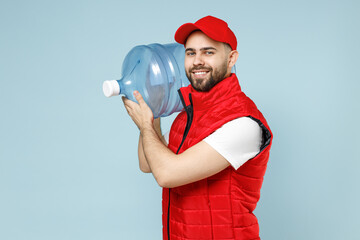 Professional delivery guy employee man in red cap white T-shirt vest uniform workwear work dealer courier hold water bottle isolated on pastel blue color background studio portrait. Service concept