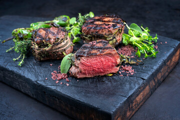 Traditional barbecue dry aged angus medaillon beef filet steak natural with herbs and red wine salt served as close-up on a charred wooden board