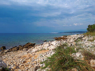 Fototapeta na wymiar Rocky coastline with grass and adriatic sea against blue sky on Kijac beach on Krk island, Croatia.