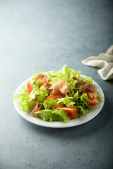 Healthy green salad with tomato and prosciutto