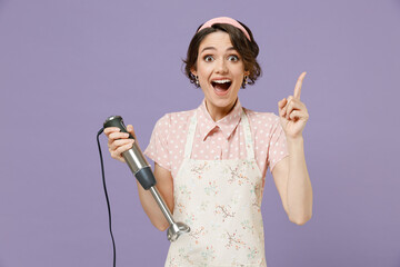 Young insighted proactive housewife housekeeper chef cook baker woman in pink apron hold blender point finger up with great new idea isolated on pastel violet background Cooking food process concept