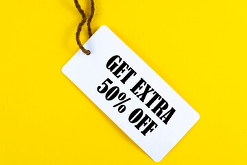 GET EXTRA 50 OFF percent text on a white tag on a yellow paper background