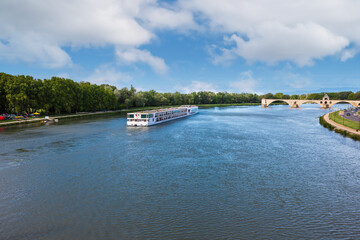 White cruise ship on the Rhone River near the Saint-Benezet Bridge. Avignon, France