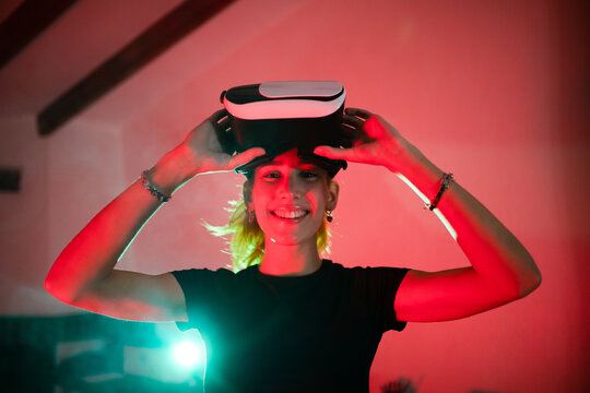 Smiling female in VR glasses in neon room