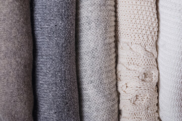 Bunch of knitted warm sweaters close-up.