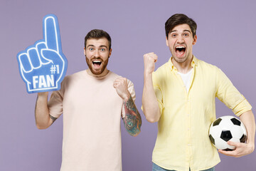 Two young overjoyed men friends together in casual t-shirt fan foam glove finger hold soccer...