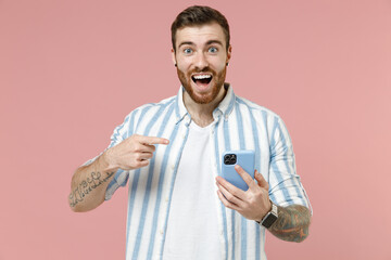 Young overjoyed satisfied surprised caucasian unshaven man 20s in blue striped shirt point index...