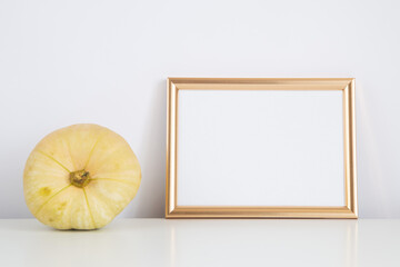 Autumn frame, background. Thanksgiving mockup with golden frame and yellow pumpkin. Halloween, fall minimal composition with copy space