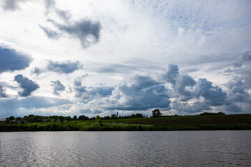 Colorful Spring Landscape On The Lake. Sunny day, many clouds in the sky. View of lake during sunrise